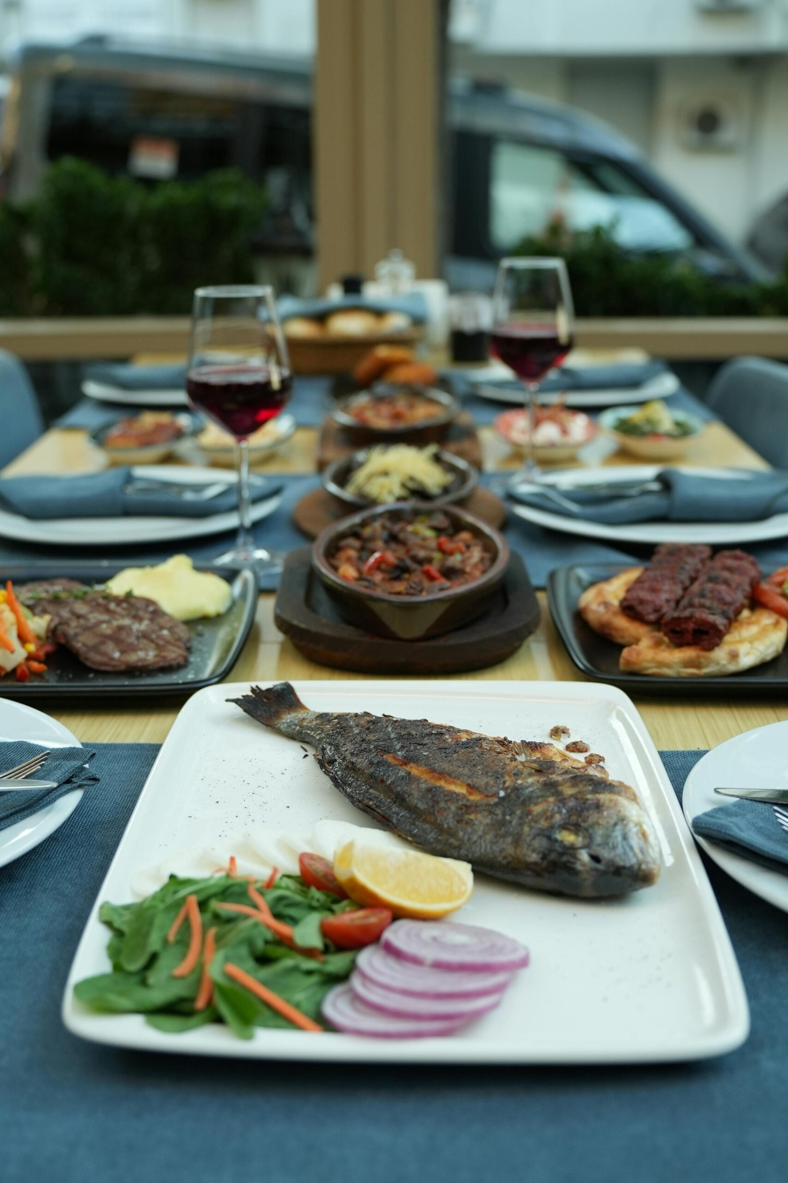 Grilled fish with vegetables on an elegant dining table set with wine, showcasing a delightful dining experience.